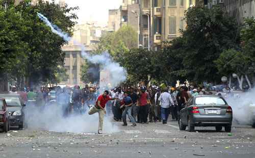 Um torcedor do deposto presidente Mohamed Morsy lança uma lata de gás lacrimogêneo em direção à polícia durante os confrontos no centro do Cairo