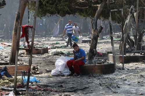 Um menino senta-se em meio a restos de um acampamento de protesto em frente à queimada Rabaa Adawiya mesquita no Cairo, polarizada e em turmoil