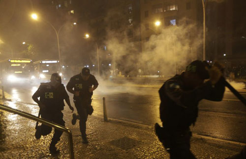 Policiais militares correm durante um confronto com manifestantes em protesto no Rio de Janeiro