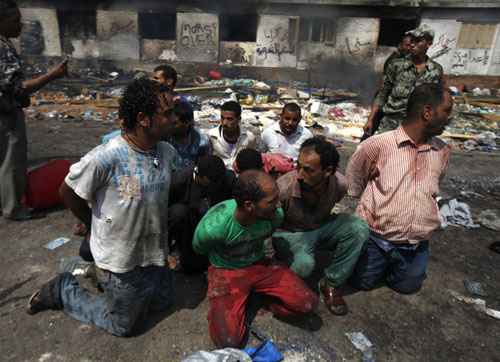 Suspeitos são detidos perto de um edifício queimado, no Cairo