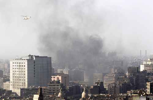 Helicóptero militar sobrevoa nuvens de fumaça na Praça Cairo durante manifestações que levou milhares de egípcios às ruas