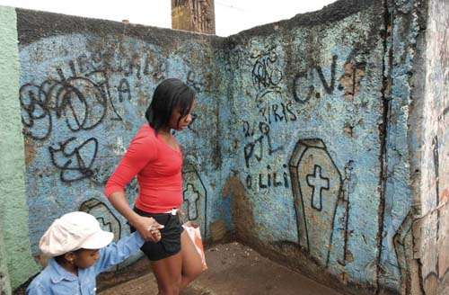 População da favela de Vigário Geral passa uma parede com grafites que lembram o massacre de 21 pessoas na comunidade, em 2009