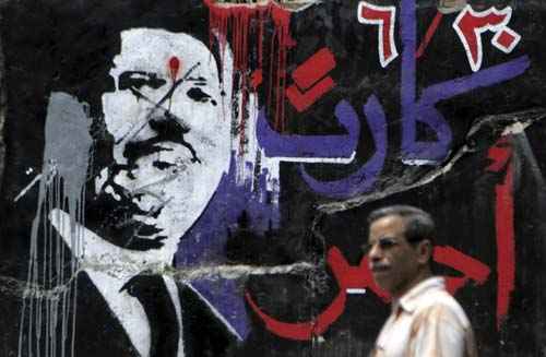 Homem caminha em frente de grafite do presidente egípcio deposto, Mohamed Morsy, no centro de Cairo