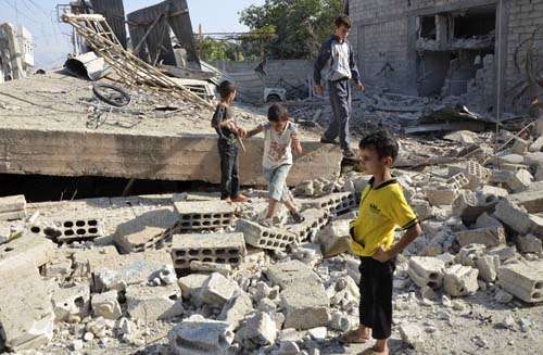 Meninos andam sobre os escombros de edifício que foi bombardeiado por parte das forças leais ao presidente da Síria, Bashar al-Assad, no bairro Duma de Damasco