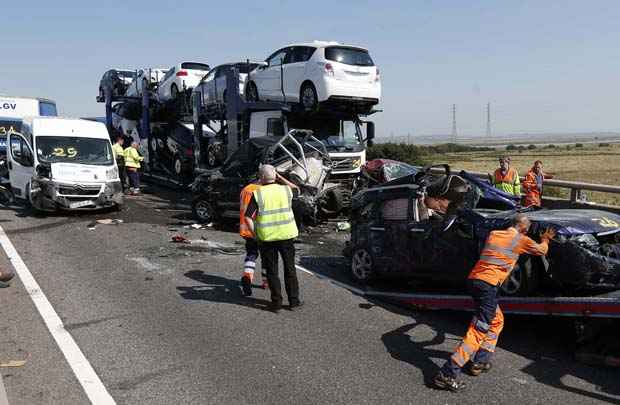 Um trabalhador de resgate empurra um carro para um caminhão de recuperação entre os destroços de alguns dos 100 veículos envolvidos em colisões múltiplas, na Ponte Sheppey,em Kent, no leste de Londres