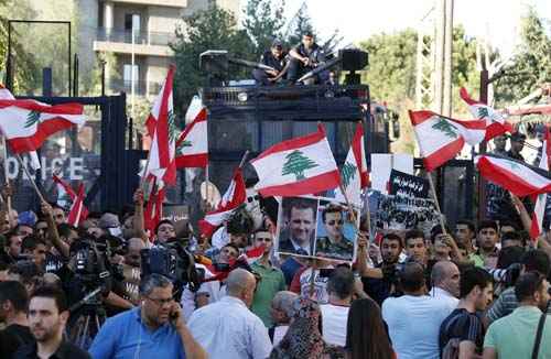 Ativistas carregam cartazes, bandeiras libanesas e fotos de presidente da Síria, Bashar al-Assad em protesto perto da embaixada dos EUA em Awkar, ao norte de Beirute