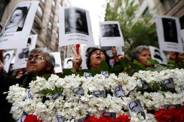 Manifestantes seguram cartazes com imagens de parentes, que foram vítimas de abusos dos direitos humanos durante os anos ex-general Augusto Pinochet