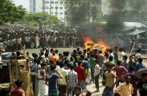 Trabalhadores ateam fogo em um banco e bloqueiam rua durante um protesto em Gazipur