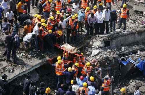 Equipes de resgate usam uma maca para transportar uma mulher que foi resgatada dos escombros no local de um edifício residencial desabou em Mumbai