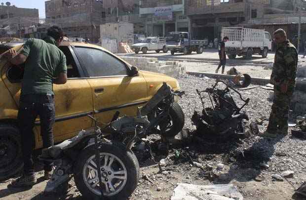 Policial examina restos de veículo que foi usado como carro-bomba em Sadr City, em Bagdá