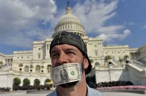 Manifestante cobre boca com nota de dólar em protesto em frente ao Capitólio dos Estados Unidos em Washington