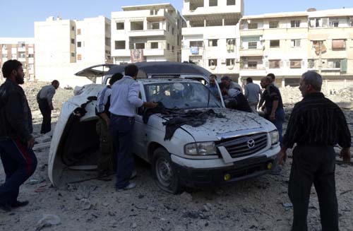 Homens buscam vítimas dentro de um carro danificado depois  um suposto ataque aéreo das forças leais ao presidente sírio, Bashar Al-Assad, na cidade Hammouriyeh na zona rural de Damasco