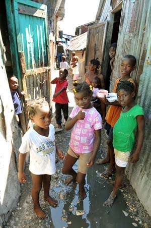 Crianças descalças em meio ao esgoto de favela de Porto Príncipe: no Haiti, a população vive com o perigo da cólera