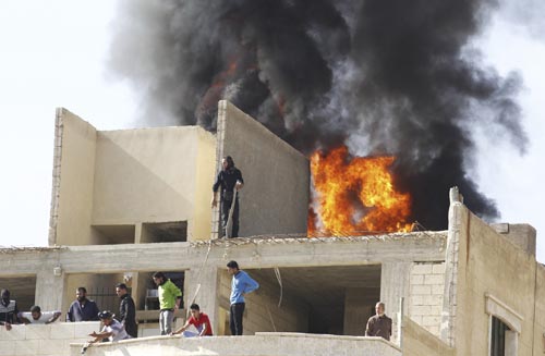 Civis e bombeiros tentam apagar incêndio em edifício que teria sido bombardeado por forças leais ao presidente Bashar Al-Assad, em Raqqa