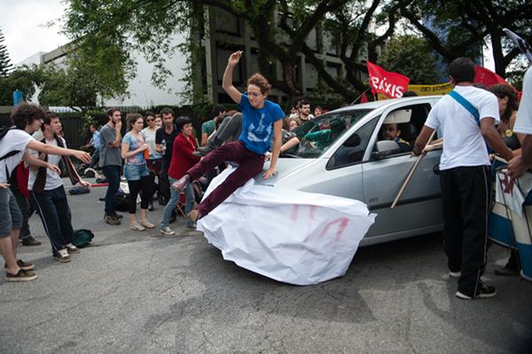 Carro avança em estudantes da Universidade de São Paulo (USP), que bloqueavam um dos portões da universidade em protesto por eleições diretas para reitor e pelo fim do convênio da USP com a PM