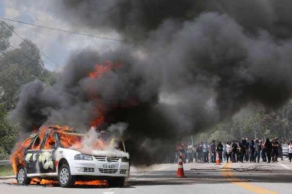 Carros da PM e da imprensa foram depredados e queimados. Várias pessoas ficaram feridas