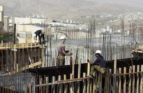 Operários trabalham em canteiro de obras de Ramat Shlomo, assentamento judaico religioso na Cisjordânia