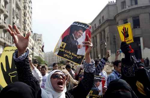 Simpatizantes de Morsy seguram cartazes diante do Supremo Tribunal egípcio, no Cairo