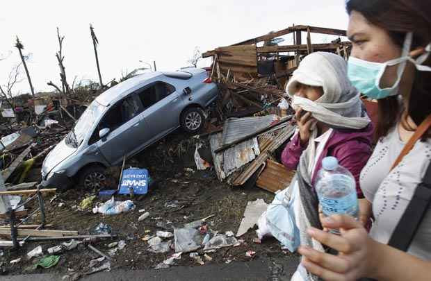 Mulheres passam por escombros deixados depois da passagem do tufão Haiyan, em Tocloban