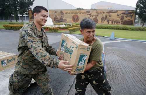 Militares carregam mantimentos que serão transportadas às vítimas de super-tufão Haiyan, em Manila