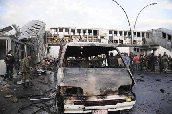 Pessoas se reúnem em torno de destroços após eplosão de carro-bomba em estação de ônibus em Soumariya, perto de Damasco