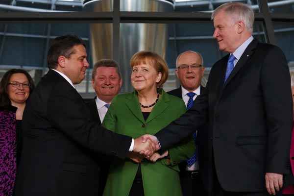 A chanceler alemã, Angela Merkel (C) sorri para aperto de mão entre o presidente da União Democrata Cristã (CDU), Horst Seehofer (D), e líder do Partido Social Democrata (SPD), Sigmar Gabriel, após assinarem acordo