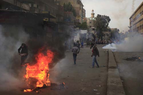 Partidários da Irmandade Muçulmana e deposto presidente egípcio Mohamed Morsy correm perto de pneus em chamas de gás lacrimogêneo disparados pela polícia e exército durante os confrontos em El-Talbyia, perto da Praça Giza, ao sul do Cairo