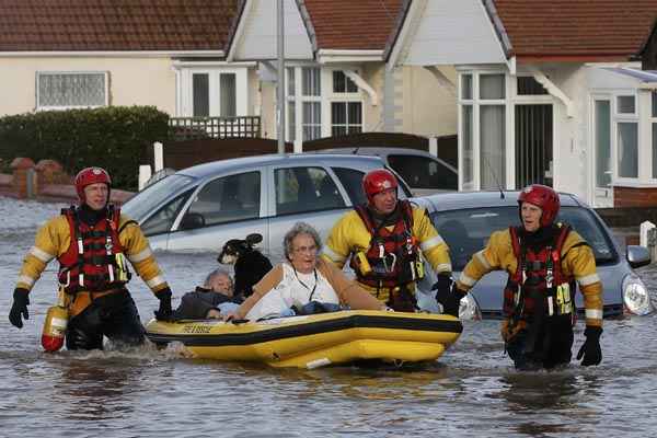 Equipe de emergência retira moradores em barco inflável em local inundado