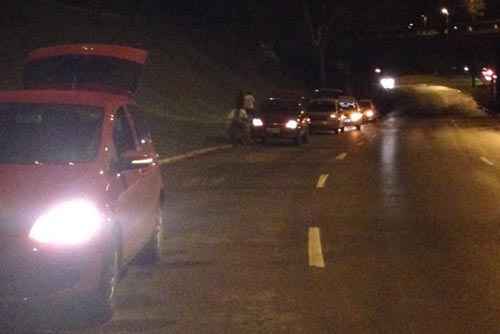 Motoristas encostam carros no meio fio da L3 Norte para avaliarem prejuízos causado pelo buraco