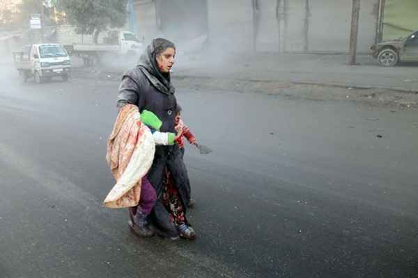 Mulher síria ferido anda com seus filhos após os ataques aéreos sobre uma zona rebelde da cidade devastada pela guerra norte de Aleppo, em 15/12