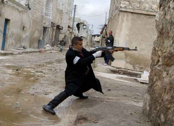 Um rebelde sírio aponta sua arma durante confrontos com as forças do governo nas ruas perto do aeroporto internacional de Aleppo