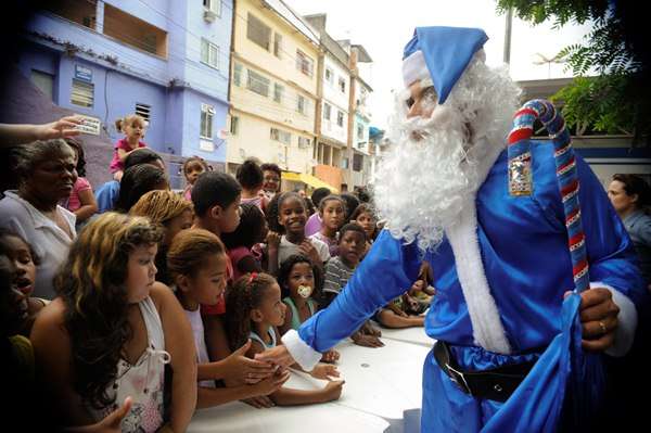 Organizado pela UPP do Morro dos Macacos, em Vila Isabel, policiais fazem festa de Natal, se vestem de Papai Noel e gnomos e distribuem presentes doados por padrinhos e madrinhas da comunidade