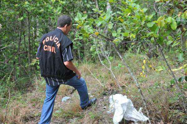 Policial civil indica o lugar onde o crime foi cometido, dentro de uma mata fechada, no Morro do Frota