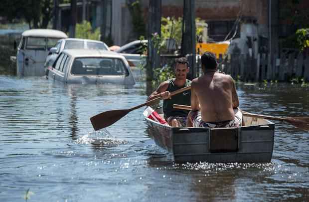 Após forte chuva, homens remavam em rua inundada de Vila Velha, Espírito Santo