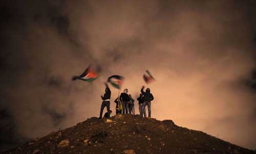 Palestinos acenam sua bandeira nacional enquanto aguardam a libertação de prisioneiros palestinos