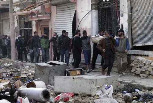 Homens carregam o corpo de uma pessoa baleada por ativistas na área sitiada de Homs, na Síria