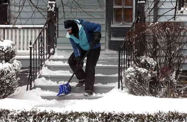 Morador tenta retirar neve de frente de casa na cidade de Buffalo, NY