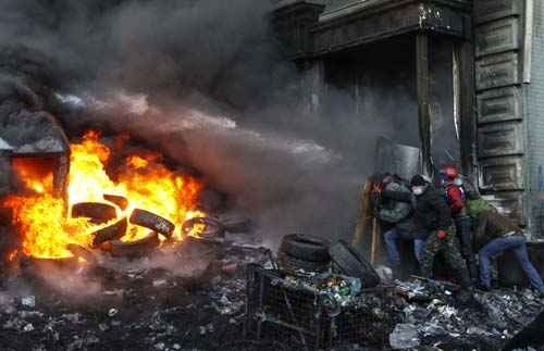 Manifestantes jogam água em um carro de bombeiros no local de confrontos com a polícia, em Kiev