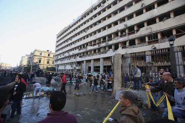 Policiais e pessoas se reúnem em frente ao prédio danificado no Cairo