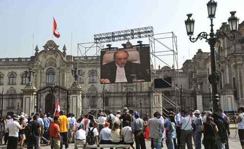 População assiste em um telão a leitura da decisão sobre a disputa marítima entre Peru e Chile pelo tribunal de Haia, em frente ao palácio do governo em Lima