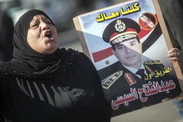 Mulher carrega cartaz do candidato à presidência marechal Abdel Fattah al-Sisi: o assassinato do general ocorre um dia depois do exército ter oficializado a candidatura do comandante