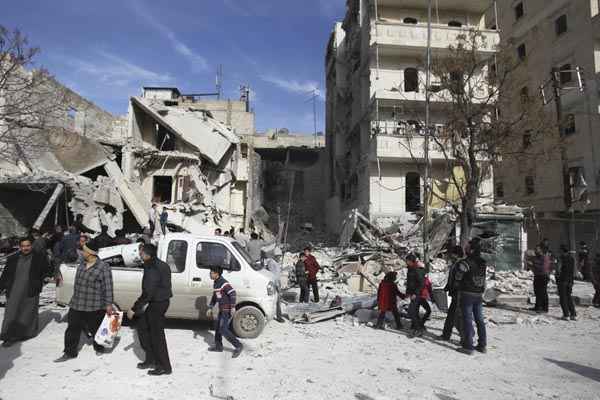 Pessoas andam em local que ficou danificado após ataque no bairro de Al-Ansari, em Aleppo