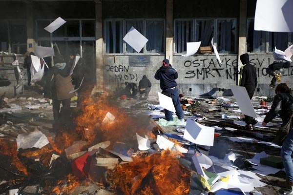 Grupo de manifestantes se reúnem em frente a prédio que foi saqueado, em Tuzla