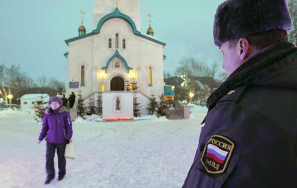 Uma foto tirada em 9 de fevereiro de 2014 mostra um policial olhando para uma mulher andando perto da catedral de Sakhalin