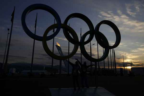 Anéis olímpicos com a chama no fundo durante os Jogos Olímpicos de Inverno de 2014 em Sochi