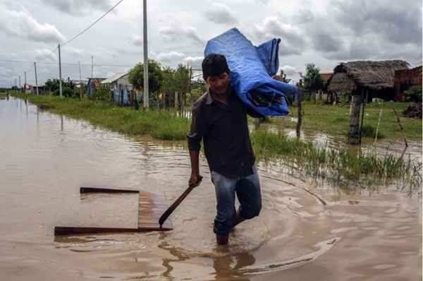 Homem leva seus pertences no bairro Villa Marin inundado, na periferia de Trindade