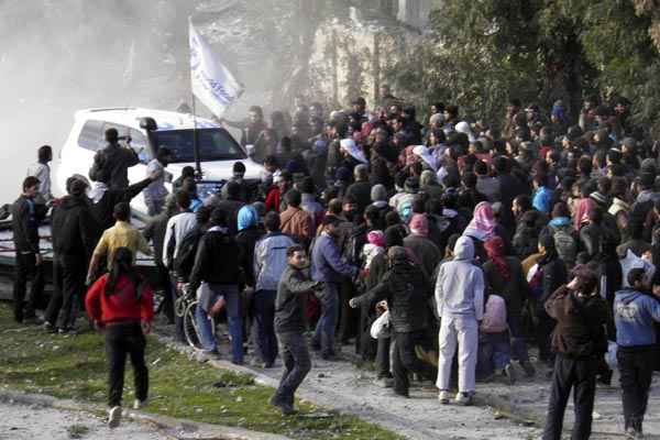 Civis se reúnem em torno de veículo das Nações Unidas enquanto esperam para serem levados de área sitiada de Homs