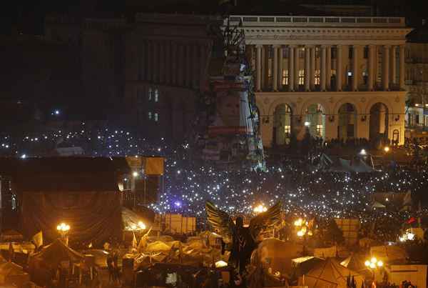 Manifestantes seguram telefones celulares durante um memorial para as vítimas dos confrontos de quinta-feira (20/2) realizada na Praça da Independência, em Kiev 21 de fevereiro.