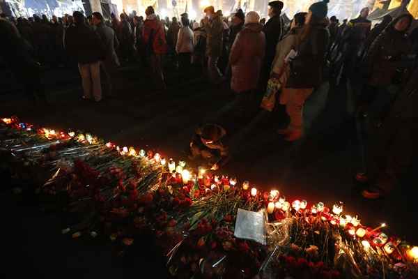 Criança acende vela em um memorial para os mortos na Praça da Independência