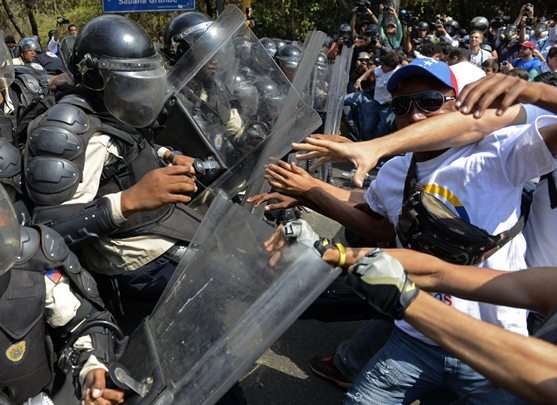 Estudantes venezuelanos e ativistas em confronto com a polícia de choque durante protesto contra o governo do presidente Nicolás Maduro